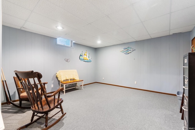 living area with carpet, baseboards, and a paneled ceiling