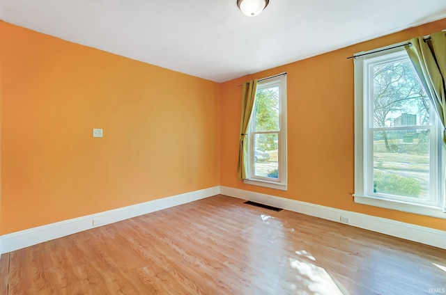 unfurnished room featuring visible vents, a healthy amount of sunlight, and wood finished floors