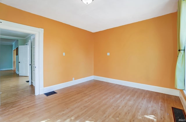 empty room with visible vents, baseboards, and light wood finished floors