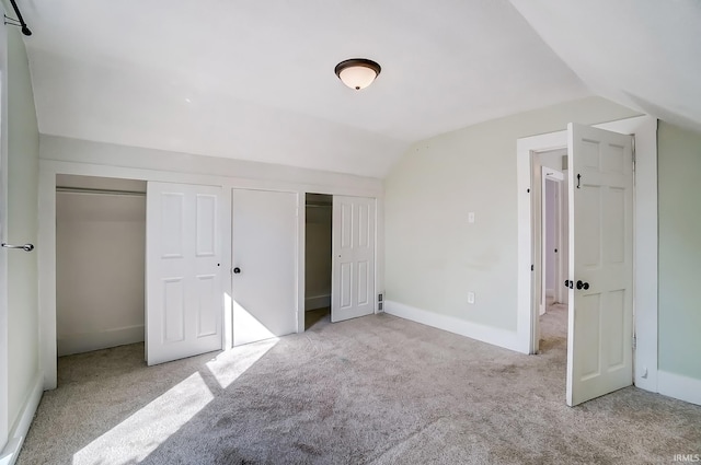 unfurnished bedroom featuring baseboards, carpet, and vaulted ceiling