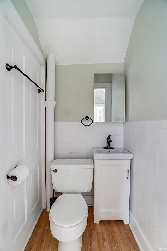 half bathroom featuring vanity, tile walls, and wood finished floors