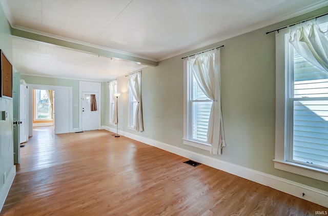 unfurnished room featuring visible vents, baseboards, light wood-style flooring, and crown molding