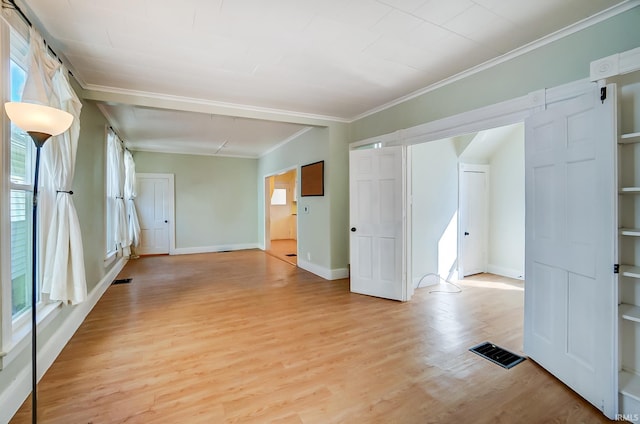 empty room with visible vents, baseboards, light wood-style flooring, and crown molding