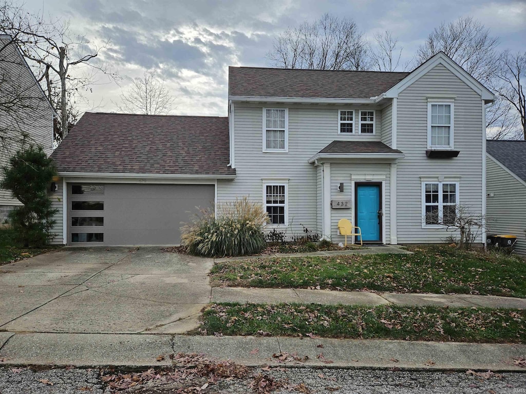 traditional-style house with a garage, roof with shingles, and concrete driveway