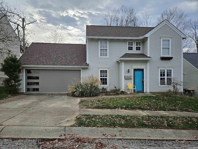 traditional-style house with a garage, roof with shingles, and concrete driveway