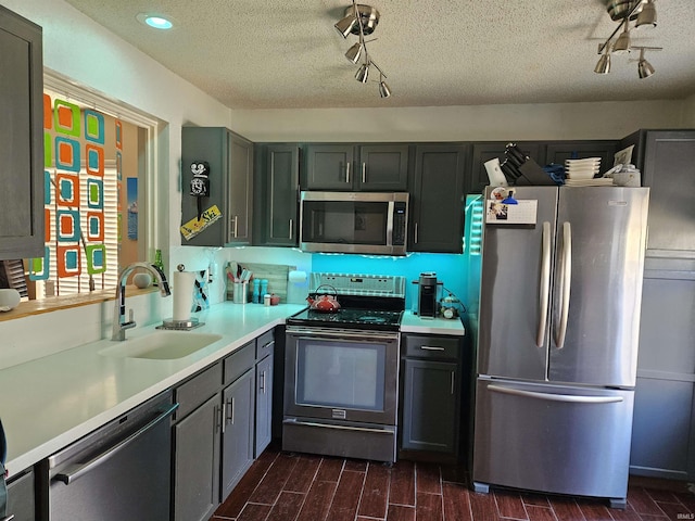 kitchen featuring wood finish floors, light countertops, stainless steel appliances, a textured ceiling, and a sink