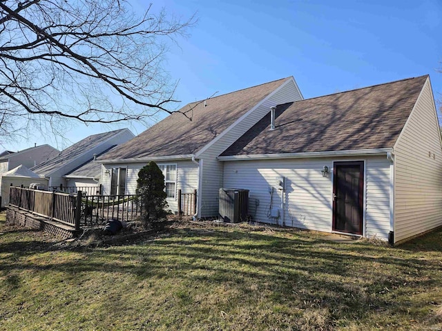 back of property with a wooden deck, a lawn, and roof with shingles