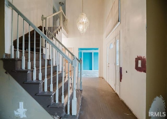 entrance foyer featuring stairway, wood finished floors, a high ceiling, and a chandelier