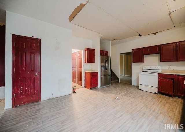 kitchen featuring white electric range oven, stainless steel fridge, and reddish brown cabinets