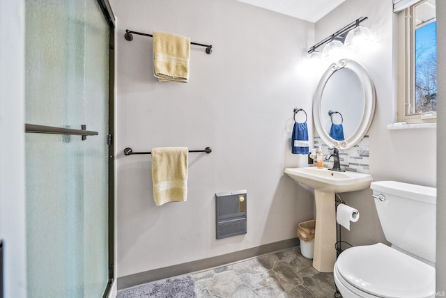 bathroom with toilet, a shower stall, heating unit, and baseboards