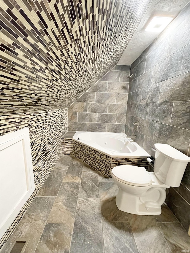 full bathroom featuring toilet, tile walls, and stone finish floor