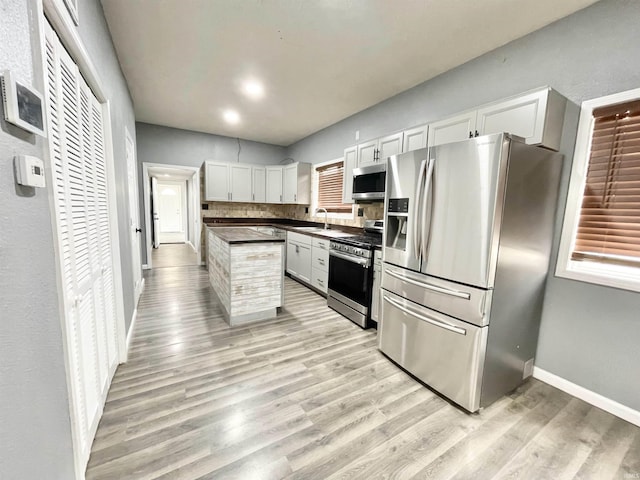 kitchen with dark countertops, light wood-style flooring, appliances with stainless steel finishes, and a sink