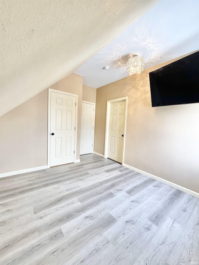 bonus room with lofted ceiling, wood finished floors, baseboards, and a textured ceiling