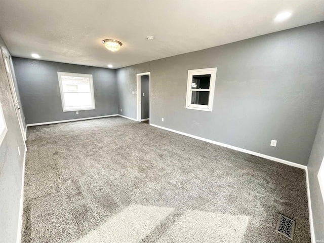 unfurnished room with baseboards, carpet floors, and visible vents