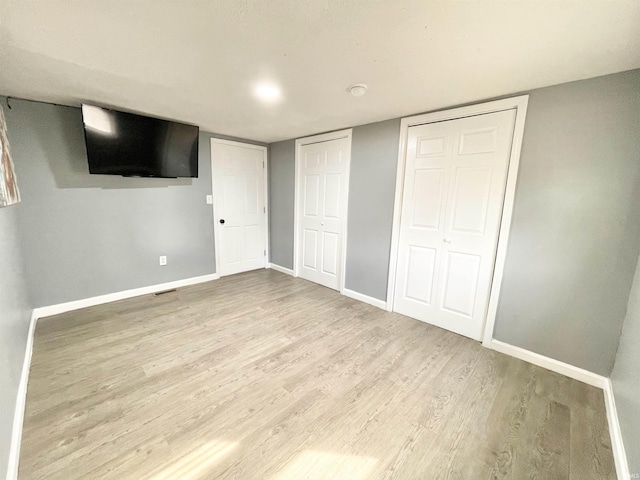 unfurnished bedroom with wood finished floors and baseboards