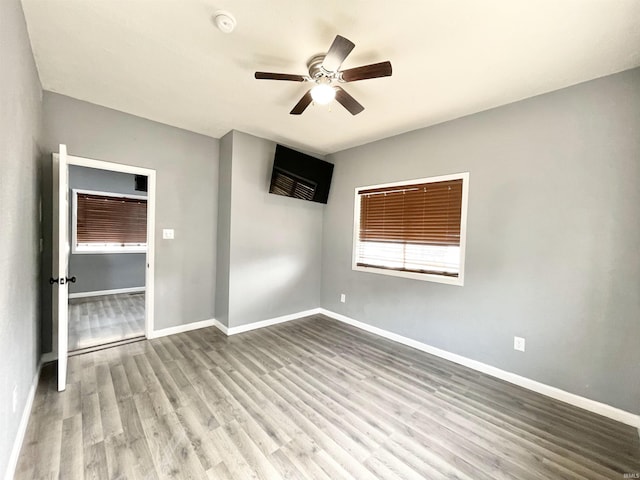 spare room featuring baseboards, ceiling fan, and wood finished floors