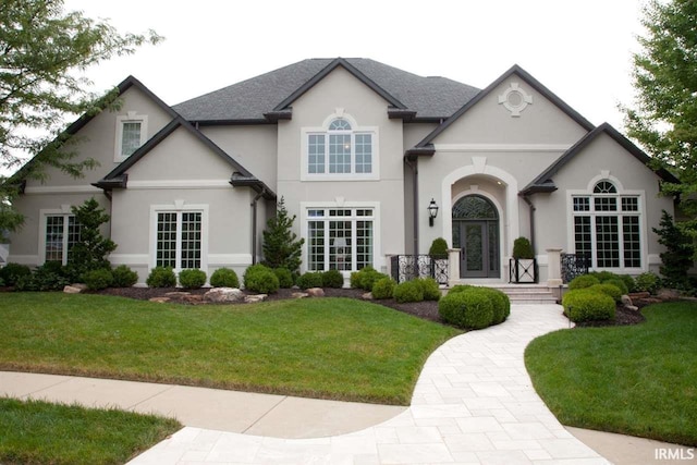 french country home featuring stucco siding, french doors, a front yard, and roof with shingles