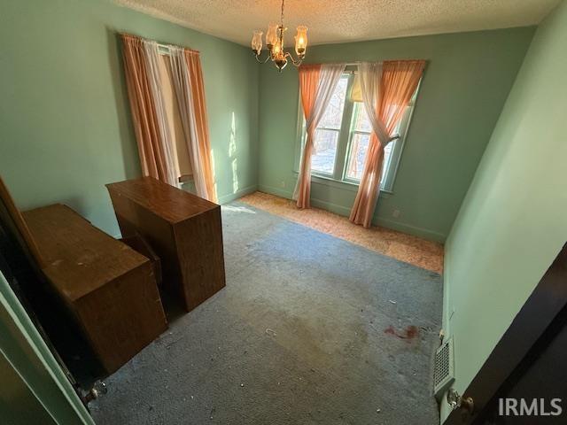 interior space featuring a notable chandelier, visible vents, a textured ceiling, and baseboards