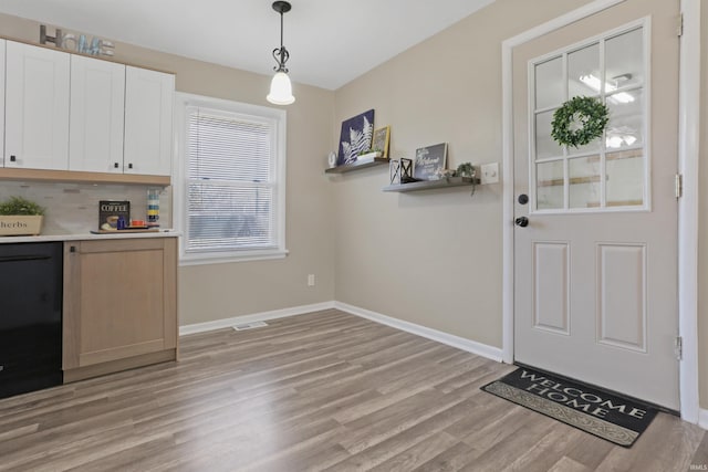 interior space with visible vents, baseboards, a dry bar, and light wood finished floors