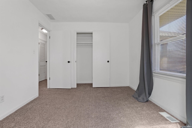 unfurnished bedroom featuring a closet, visible vents, baseboards, and carpet