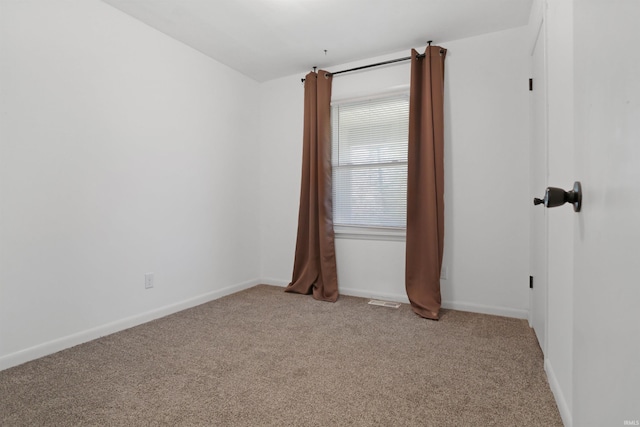 empty room with visible vents, baseboards, and light colored carpet