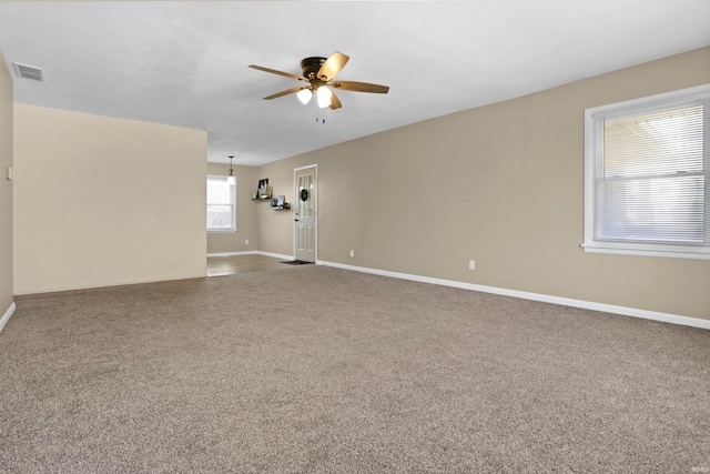 unfurnished room with visible vents, carpet floors, baseboards, and ceiling fan