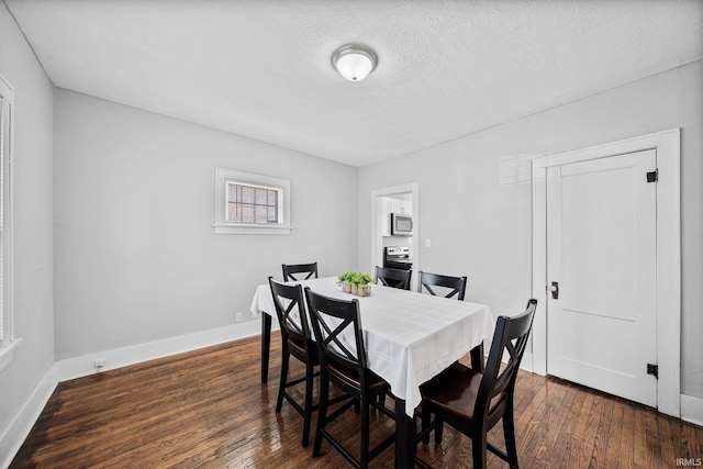 dining space featuring a textured ceiling, baseboards, and dark wood-style flooring