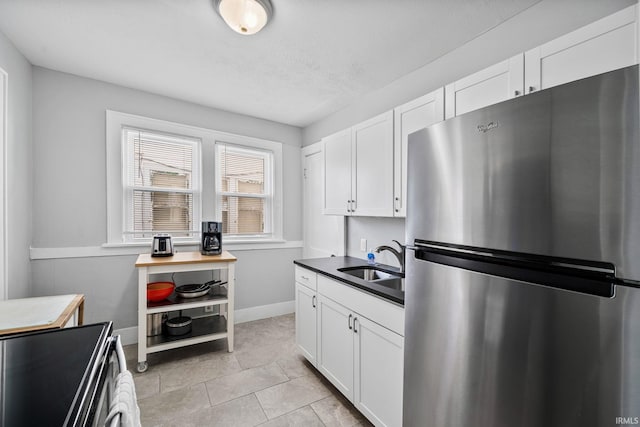 kitchen with white cabinets, appliances with stainless steel finishes, baseboards, and a sink