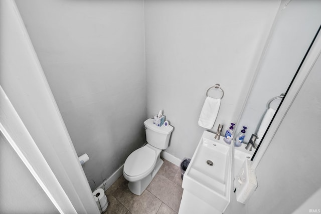 half bathroom featuring baseboards, toilet, and tile patterned flooring