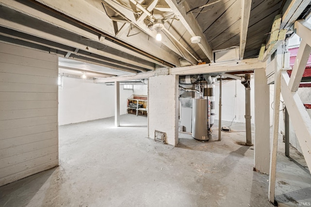 unfinished below grade area featuring wooden walls and water heater