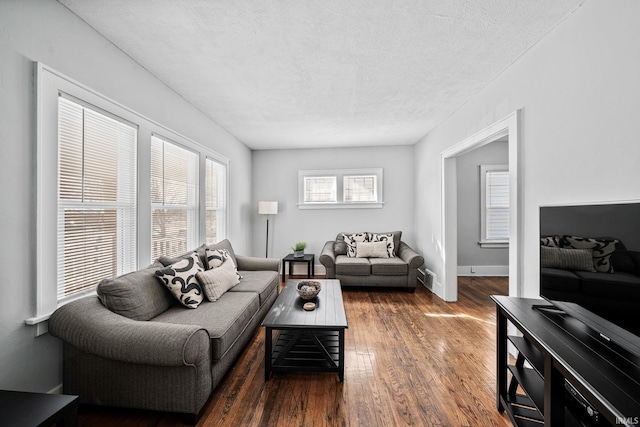 living area with visible vents, a textured ceiling, baseboards, and wood finished floors