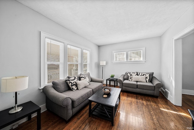 living area featuring visible vents, a healthy amount of sunlight, baseboards, and dark wood-style flooring