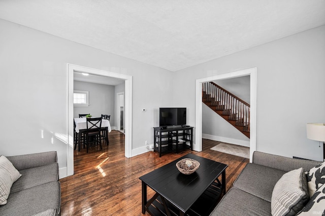 living room featuring stairway, baseboards, and wood finished floors