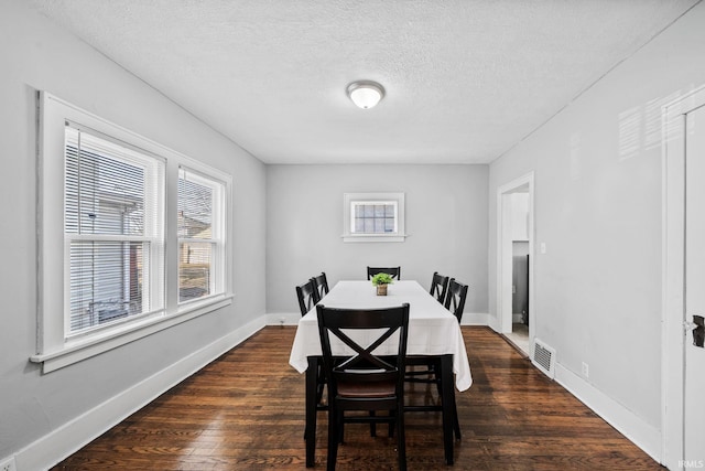 dining space featuring dark wood finished floors, visible vents, a textured ceiling, and baseboards