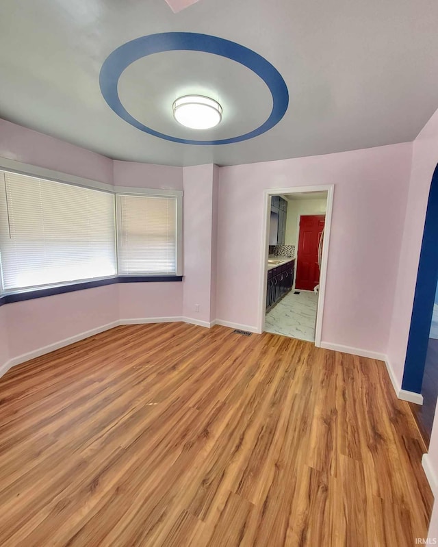 spare room featuring light wood-type flooring and baseboards