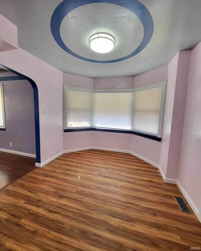 spare room featuring visible vents, baseboards, and wood finished floors