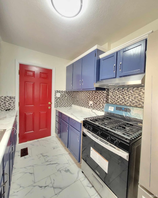 kitchen featuring under cabinet range hood, marble finish floor, blue cabinetry, and stainless steel range with gas cooktop