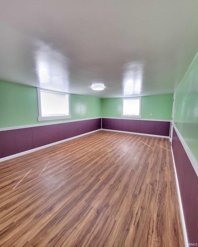 basement with wood finished floors and a wainscoted wall