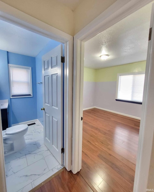 hall with visible vents, baseboards, marble finish floor, and a textured ceiling