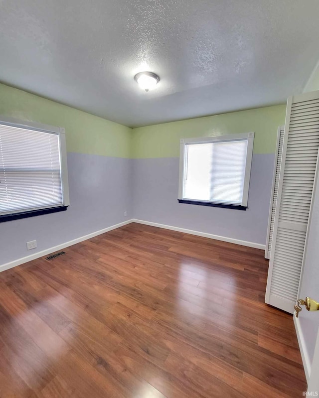 spare room with visible vents, baseboards, and wood finished floors