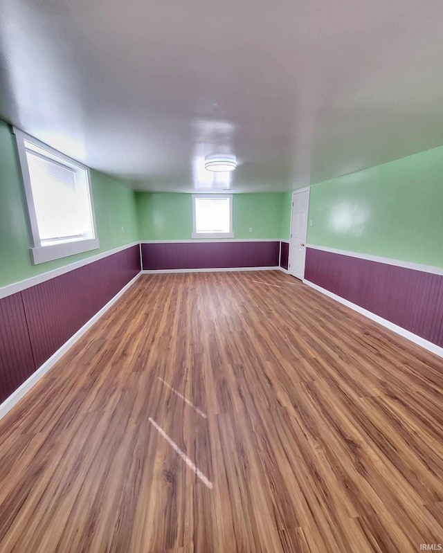 basement featuring wood finished floors, wainscoting, and wood walls