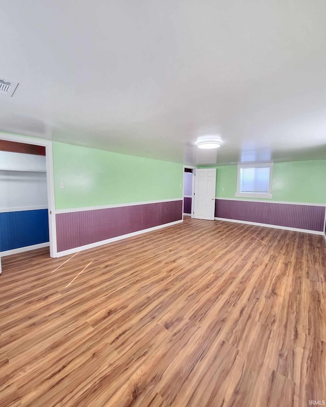 empty room featuring visible vents, wainscoting, and wood finished floors