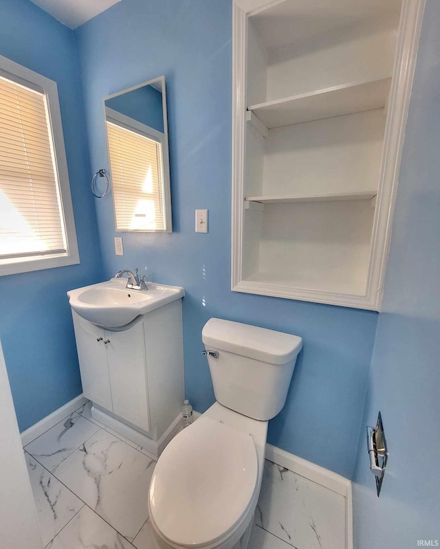 bathroom with marble finish floor, toilet, vanity, and baseboards