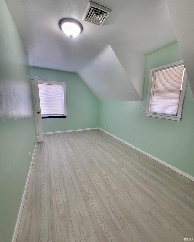 bonus room with visible vents, lofted ceiling, baseboards, and wood finished floors