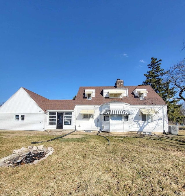 rear view of property featuring a shingled roof, a yard, central AC, and a chimney