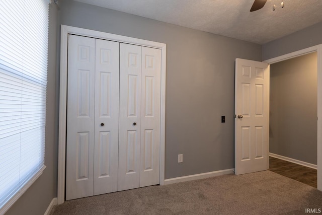 unfurnished bedroom with baseboards, carpet, a closet, a textured ceiling, and a ceiling fan