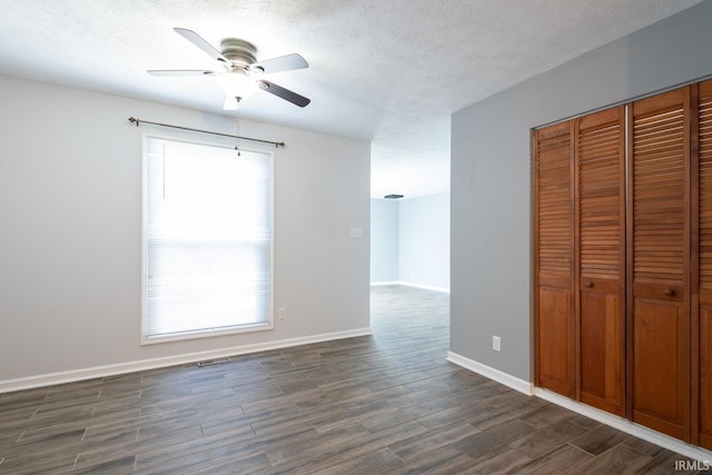 interior space featuring dark wood-style floors, a textured ceiling, a wealth of natural light, and ceiling fan