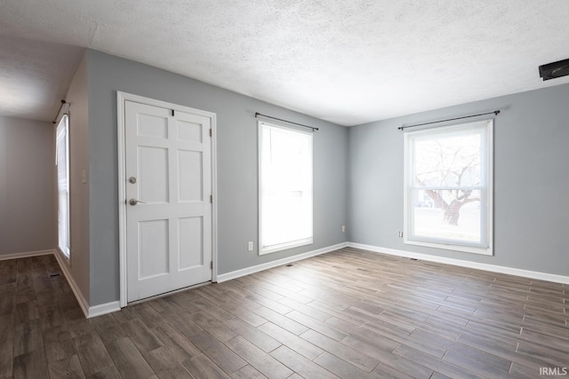 empty room featuring baseboards, dark wood-type flooring, and a textured ceiling