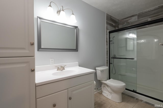 bathroom with a stall shower, toilet, vanity, and a textured ceiling