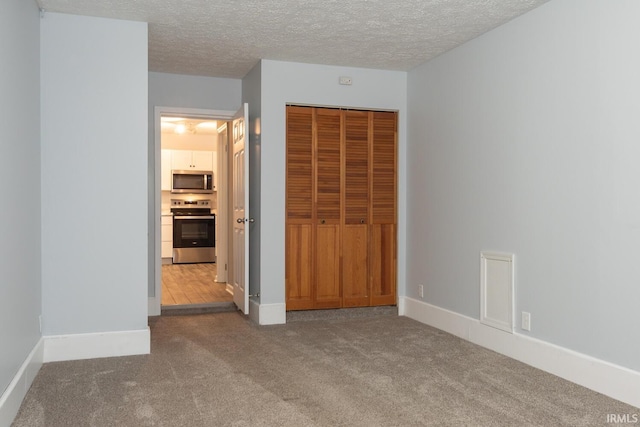 unfurnished bedroom with baseboards, carpet, a closet, and a textured ceiling